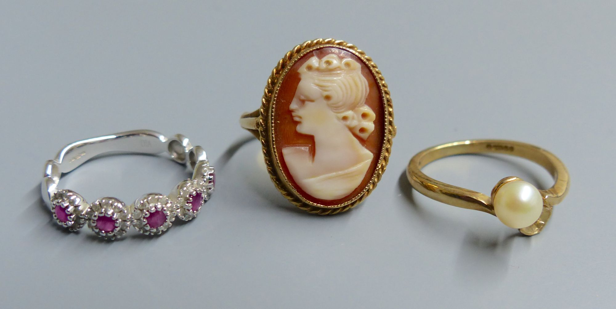 A white gold, ruby and diamond chip five cluster ring, a cameo ring and a pearl set ring